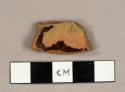 Redware sherd with black glaze on exterior and mottled lead glaze on interior