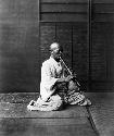 Japanese man in traditional dress playing musical instrument