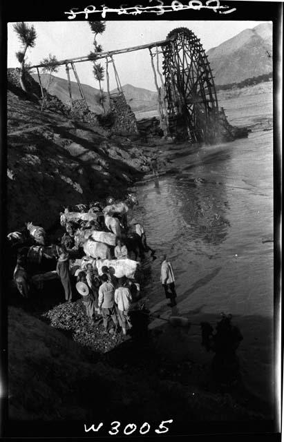 Water wheel and people working on beach