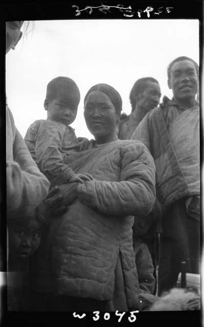 Woman holding child, with man behind