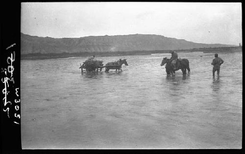 Horses, wagons and people in shallow water