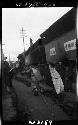 Man walks down road lined with people, carrying cargo