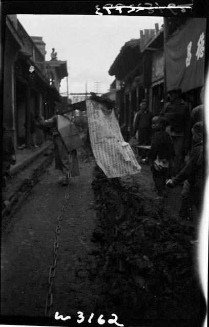 Person walks with cargo, trailing chain