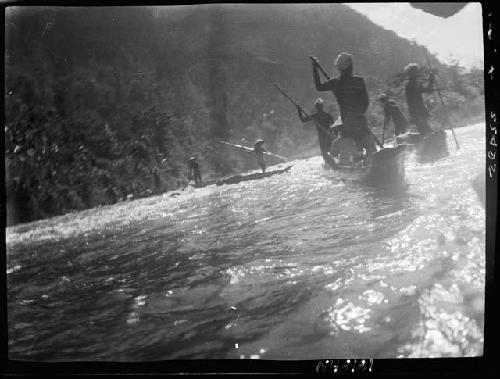 People row canoes on river