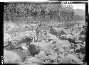 People standing on rocks by river pull ropes