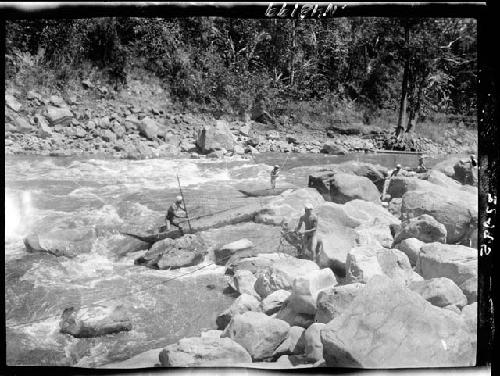 People work with boats from rocks on shore