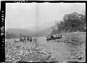 Boat on water, with people watching from riverbank