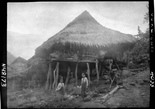 Children stand outside hut