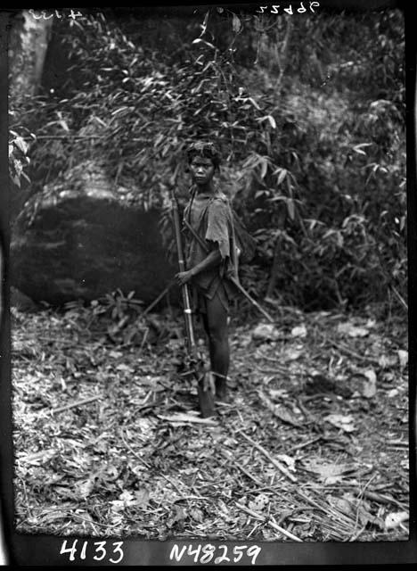 Boy stands outside holding weapon