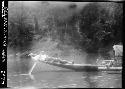 Person laying on back of canoe on river