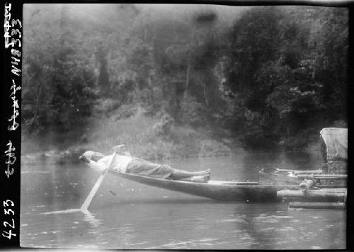 Person laying on back of canoe on river