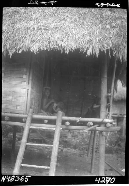 Person seated inside hut