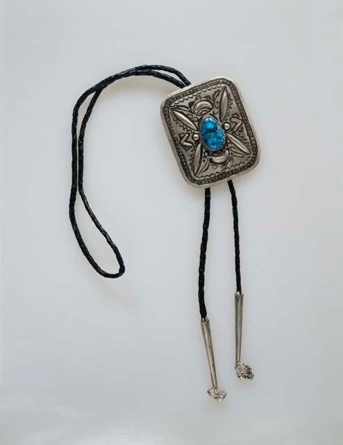 Bolo made from a rectangular silver belt buckle with overall stamped designs, on