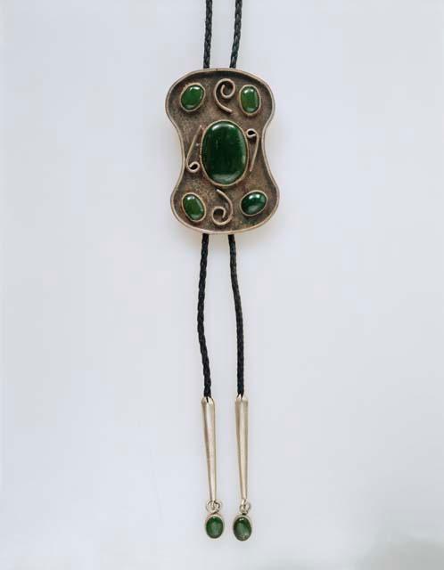 Bolo, silver shield in a figure-8 shape, applied dec. & inlaid green stones