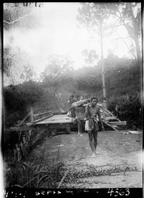 People carry materials across bridge