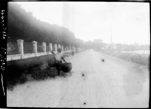 Person carrying baskets down road