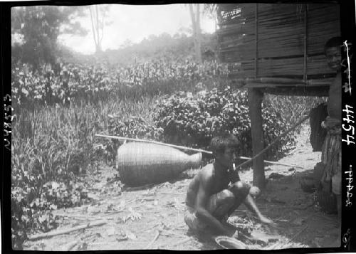 Boy kneels outside hut