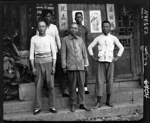 Five men stand on steps outside building