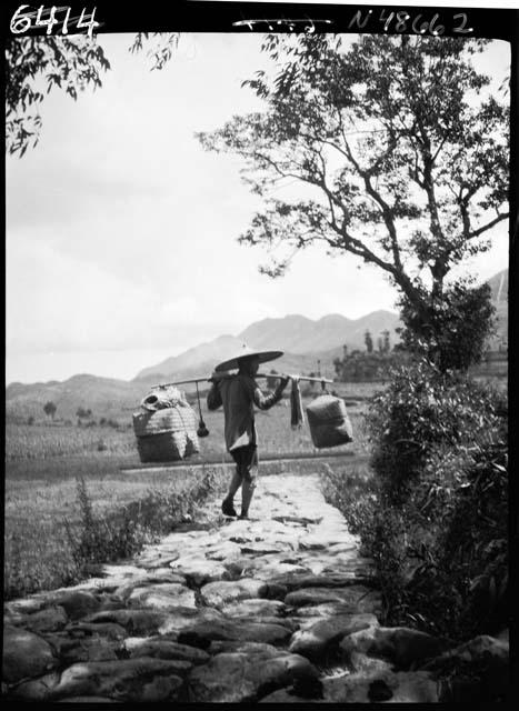 Person carries buckets down road