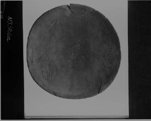 Wooden disk: human figures incised in convex side, inlaid with sheet, turqouise and glass beads. Interior decorated with incised fish.