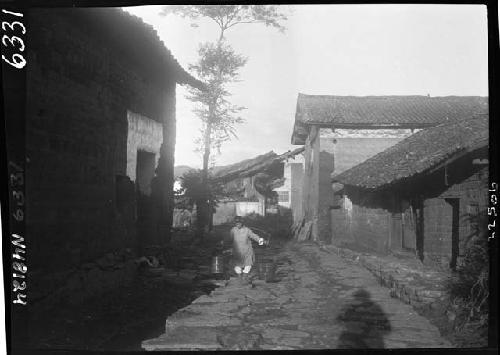 Person carrying buckets down road