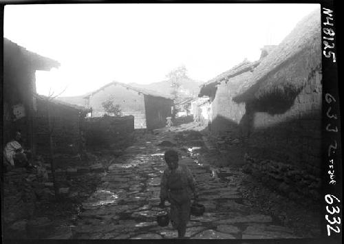 Child carrying objects down road