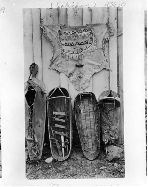 Old style woman's buckskin shirt and four baby carriers.