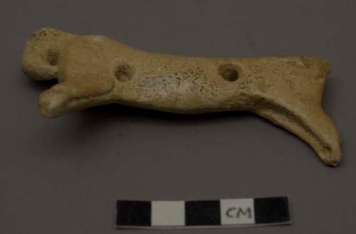 Cast of bone carving of cat-like animal with holes for suspension