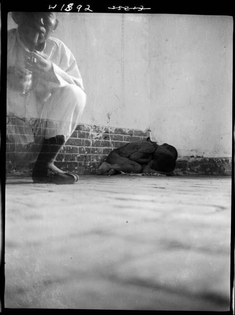 Person seated and children sleeping on ground