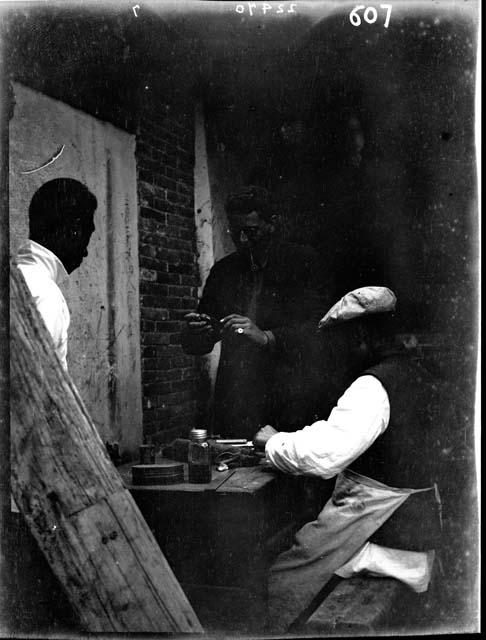 Three people inside room, working around table