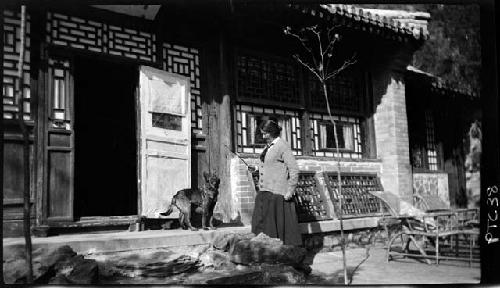 Woman stands outside building with dog