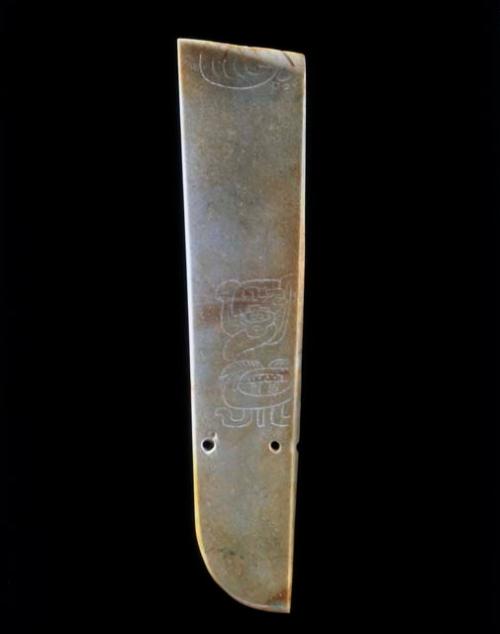 Half a Maya jade belt plaque with an incised glyphic design and two perforations