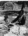 Woman and child shucking corn