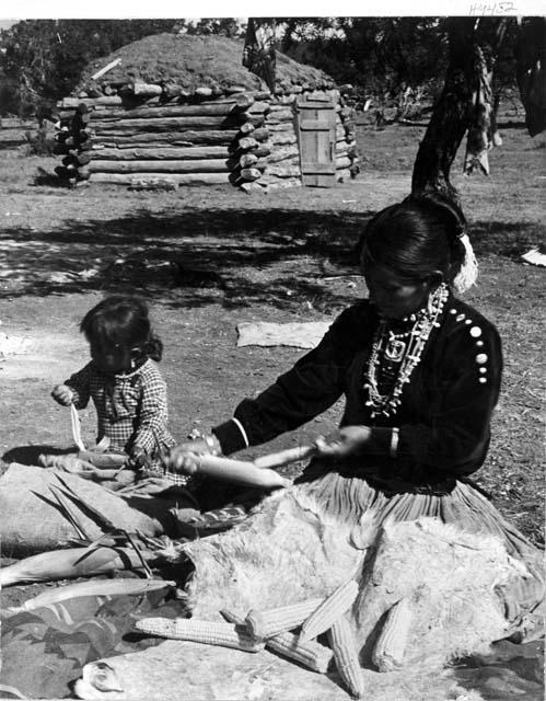 Woman and child shucking corn