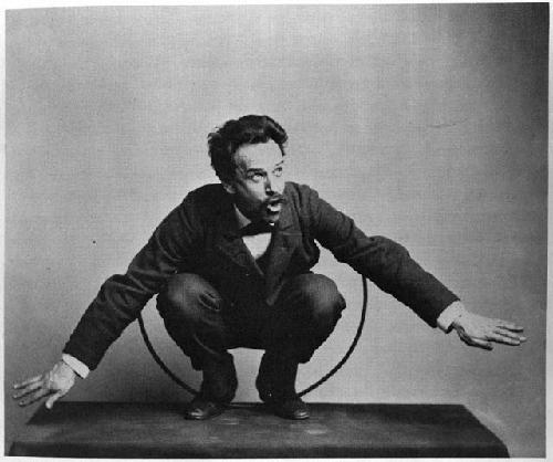 Portrait of man crouching, with arms extended and hoop around body