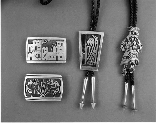 Silver overlay Pueblo scene belt buckle; silver overlay belt buckle of two flute players; silver overlaid snake dancer bolo ketch with cord; parrot overlay and multi-stone inlaid bolo ketch with cord.