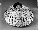 Coiled bowl-shaped basket with lid representing Seminole woman.