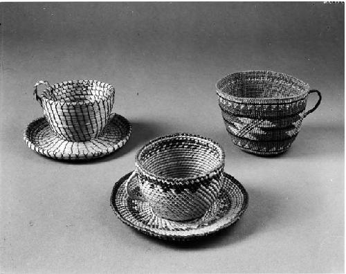 Basketry cup and saucer; coiled fully beaded trinket basket of willow with squash blossom motif; twined teacup-shaped basket, with handle: geometrical motifs.