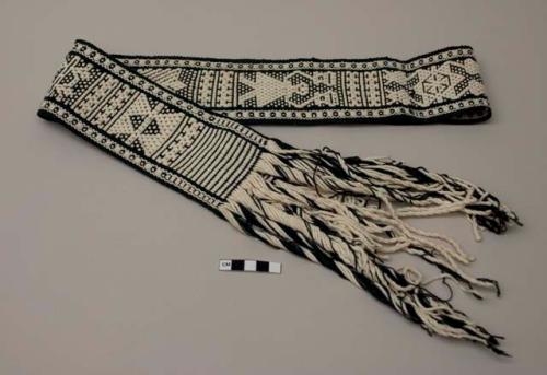 Waistband, black ground with white human forms, two white patterned stripes at sides