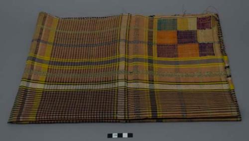 Textile, black, tan, and yellow plaid with colorful square design in two corners