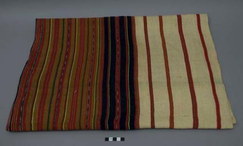 Textile, two panels sewn together, tan, navy, red, white, green and yellow solid and jaspe thin and thick stripes. The white areas are stained and have darkened over time.