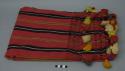Textile, red ground with black, yellow, green, and tan solid and jaspe stripes, multi-color tassel trim. The textile has some stained areas and an odd odor.
