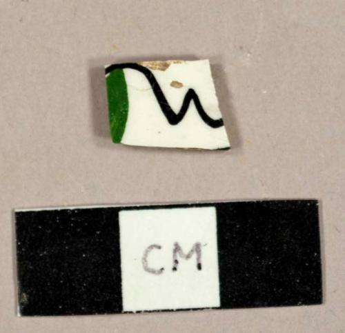 Hand painted green and black whiteware sherd, possibly a floral design