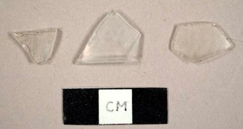 Colorless curved glass fragments, including one body fragment and a base fragment from a hurricane lamp