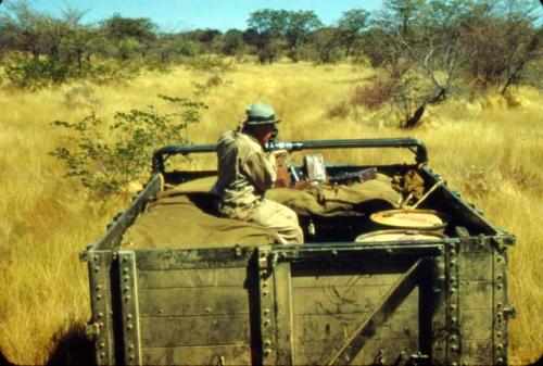 Laurence Marshall taking a photograph from the top of an expediton truck (Dodge)