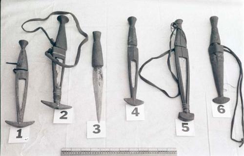 Six knives, five of them in sheathes, with a ruler for measurement