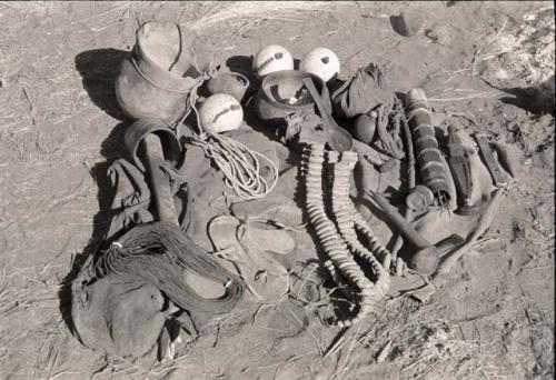 "Gao Medicine's" possessions, including rattles, oracle disks, an Ovambo pot, ostrich egg shells, quiver, and cord; ashes from a fire in the background