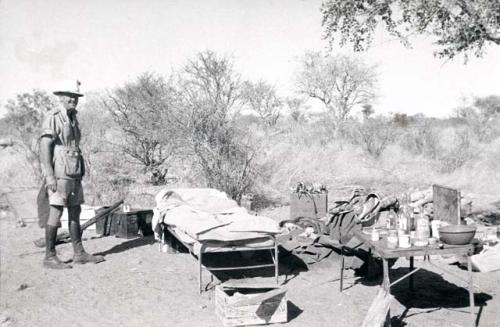 Claude McIntyre standing by his belongings in the expedition camp