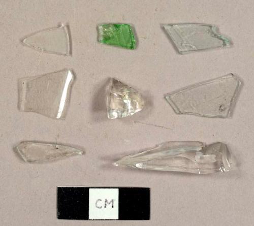 Glass fragments, including one piece of green bottle glass, three colorless flat glass fragments, and two fragments possibly from a hurricane lamp