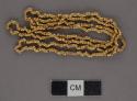 Metal necklace of beads, gold, tubular, plain, strung as necklace.